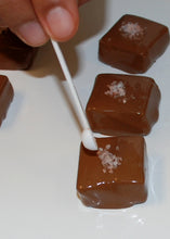 Load image into Gallery viewer, image of Himalayan salt being applied to salted Caramel piece